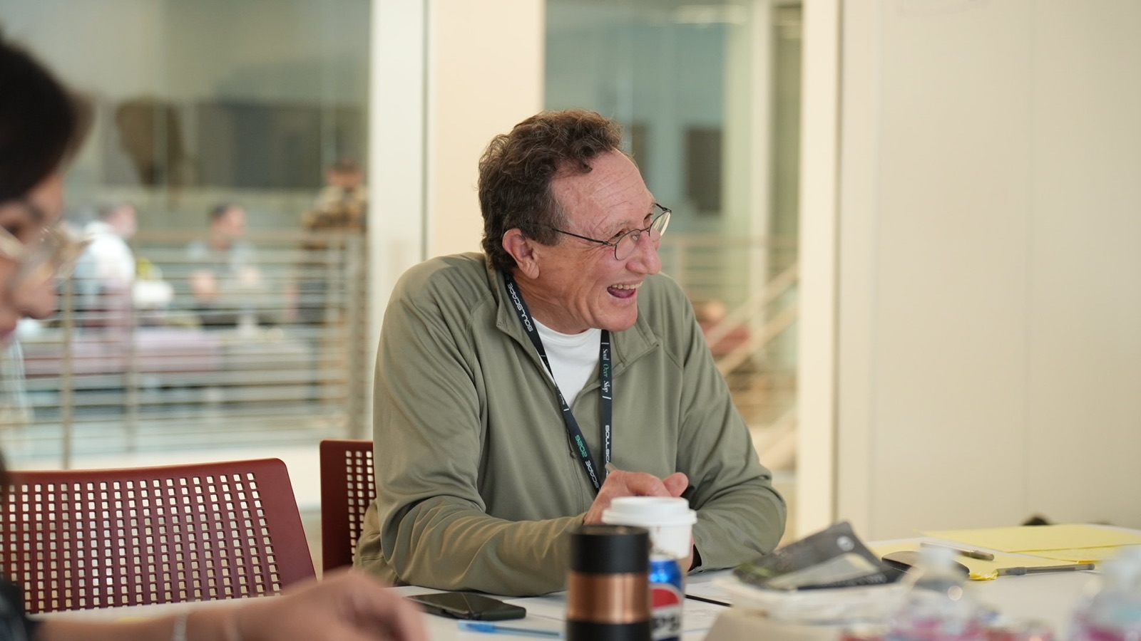 A mentor laughing with creators at a work table during the Cinema Lab