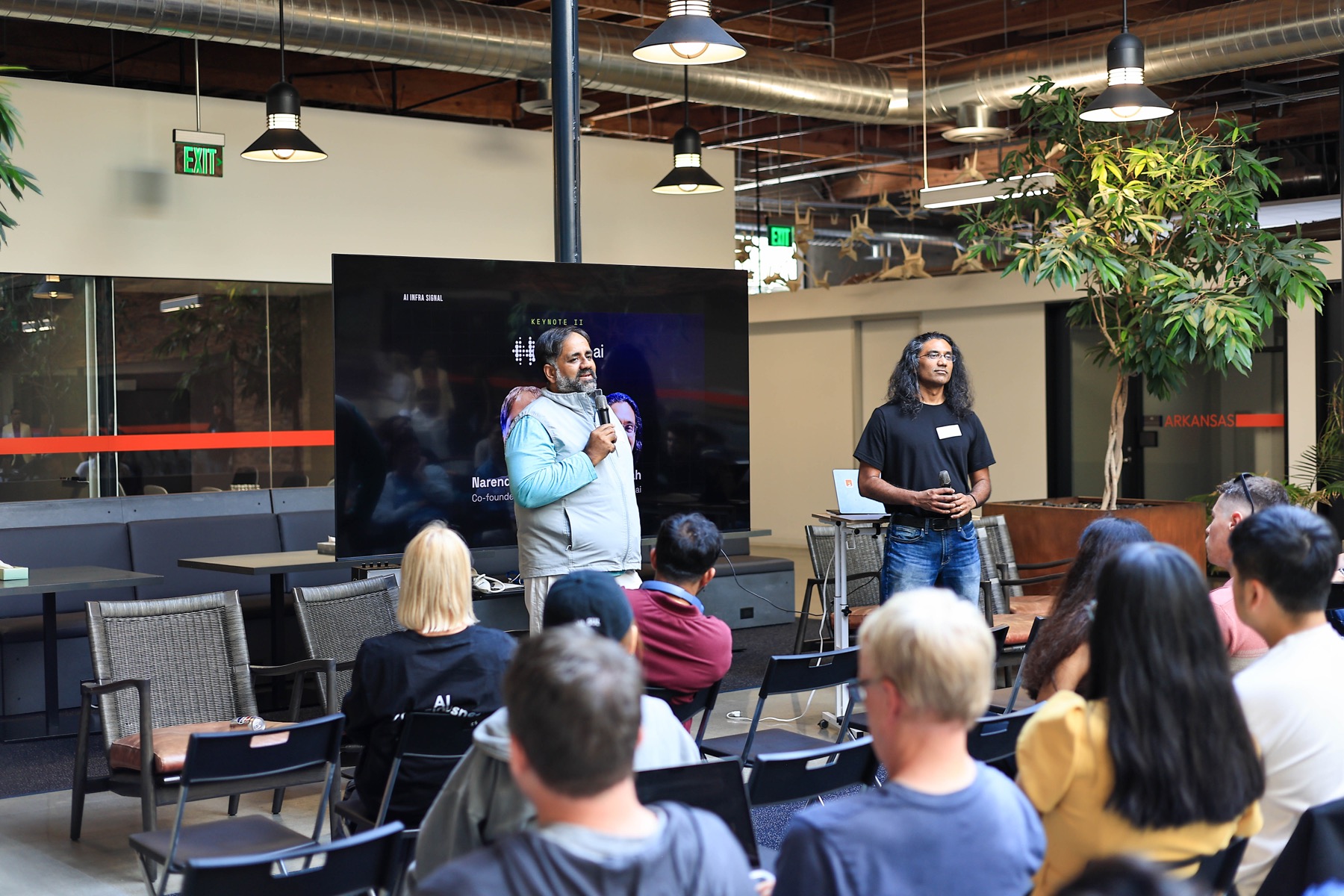 The hosted.ai keynote with two speakers and the audience at AI Infra Signal